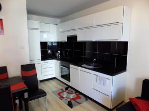 a kitchen with white cabinets and black counter tops at Wygoda in Augustów