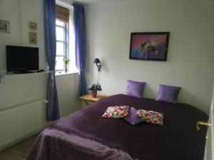 a bedroom with a purple bed with two pillows on it at Skelstrupgaard Apartments in Maribo