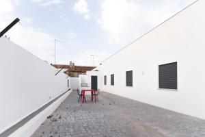 una silla roja se encuentra en el patio de un edificio blanco en Villa UA, en Pias