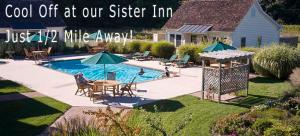 a swimming pool with tables and umbrellas in a yard at Parsonage Inn Bed and Breakfast in Saint Michaels
