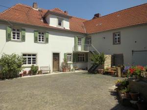 ein weißes Haus mit grünen Rollläden und einem Hof in der Unterkunft Gästezimmer Mittelgasse in Flörsheim-Dalsheim