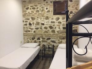 2 letti in una camera con parete in pietra di Apartamento Tolaitola a Toledo