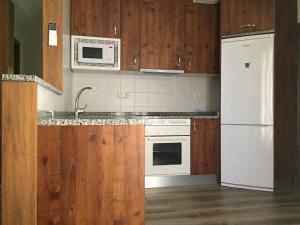 una cucina con elettrodomestici bianchi e armadietti in legno di Apartamento Tolaitola a Toledo