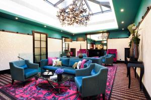 a lobby with a blue couch and chairs and a chandelier at Tiffany Hotel in Geneva