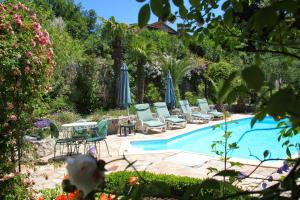 una piscina con sillas y sombrillas en un patio en Lou Pero Mousco, en Saint-Paul-en-Forêt