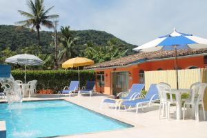 una piscina con sillas y sombrillas junto a una casa en Pousada Porto Paraiso, o seu Paraíso Escondido no Guarujá en Guarujá