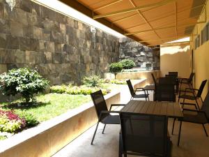 un patio con mesas y sillas y una pared de piedra. en Hotel Mirto en Puebla