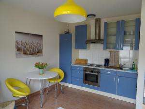 a kitchen with blue cabinets and a table with yellow chairs at Boddenpieper in Born