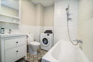 a white bathroom with a washing machine and a washer at #stayhere - Comfy & Stylish Studio with Green Patio close to Old Town in Vilnius +18 photos