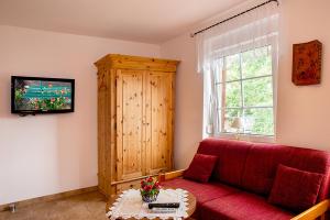 a living room with a red couch and a tv at Spreewaldpension Andreas Krüger in Schlepzig