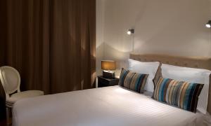a bedroom with a white bed with a lamp and a chair at Logis L'hermitage in Buzançais