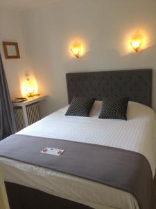 a bedroom with a large bed with two lights on the wall at Logis L'hermitage in Buzançais