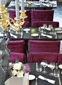 una sala da pranzo con tavoli neri e sedie viola di Logis L'hermitage a Buzançais