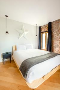 - une chambre avec un grand lit blanc et un mur en briques dans l'établissement Les Lofts St-Pierre - Par Les Lofts Vieux-Québec, à Québec