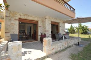 una casa in pietra con patio e ombrellone di Marina Maisonette by RentalsPro Kallithea Halkidiki a Kallithea