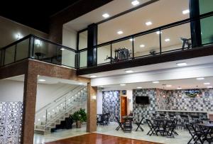 a lobby with tables and chairs and a staircase at Solar Plaza Hotel in Fernandópolis