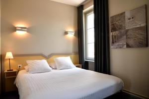 - une chambre avec un grand lit blanc et 2 oreillers dans l'établissement Logis Restaurant & Hôtel À la 12, à Delme