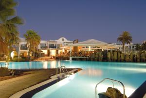 a swimming pool with blue water in a resort at Las Marismas de Corralejo in Corralejo