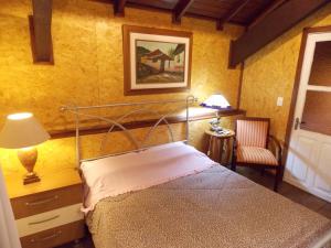 ein Schlafzimmer mit einem Bett, einer Lampe und einem Stuhl in der Unterkunft Sobrado no Centro de Canela in Canela