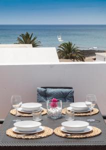 una mesa con platos y vasos y el océano en Luxury Beach Apartments, en Playa Honda