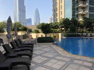 a pool with chairs and an umbrella in a city at Burj Grand Apartment - Four Bedrooms in Dubai