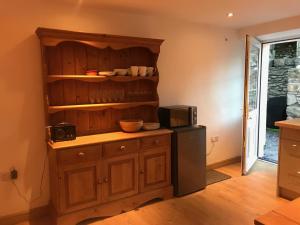 een keuken met een houten kast en een magnetron bij Plas Eryr apartment in Caernarfon