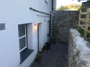a white building with a window and a stone wall at Plas Eryr apartment in Caernarfon