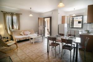 a living room with a table and a kitchen at Olive green house in Agia Pelagia