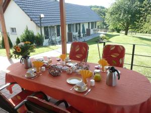 una mesa roja con platos y utensilios. en Chez Anny et Jean Au Mittelbuehl, en Reichshoffen