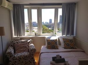 a bedroom with a bed and a couch in front of a window at A.G-Apartamenty Warszawa Centrum in Warsaw