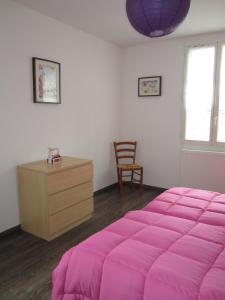 sypialnia z różowym łóżkiem i drewnianą komodą w obiekcie Côté Jardin w mieście Saint-Jean-en-Royans