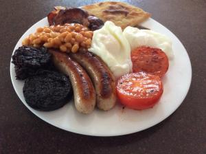 a plate of breakfast food with sausage beans and bread at Rudan Guest House in New Deer