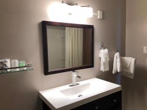 La salle de bains est pourvue d'un lavabo blanc et d'un miroir. dans l'établissement Voyageur Motel, à Thunder Bay