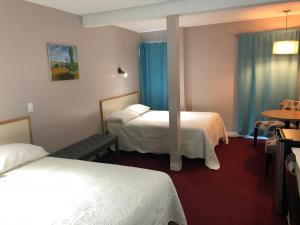 Habitación de hotel con 2 camas y mesa en Voyageur Motel en Thunder Bay