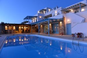 a villa with a swimming pool at night at Marble Villas in Tinos Town