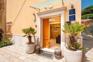 a front door of a building with palm trees in pots at Guest House Golden Goose in Rovinj