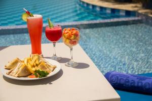 a table with two drinks and a plate of food next to a pool at Ayenda 1801 El Oceano in Cartagena de Indias