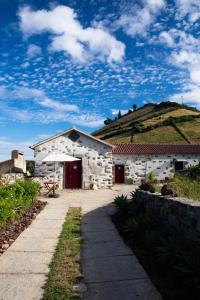 un edificio de piedra con una montaña en el fondo en Casas da Quinta, en Santa Cruz das Flores