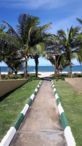 un trottoir menant à une plage bordée de palmiers dans l'établissement Village, à Guarajuba