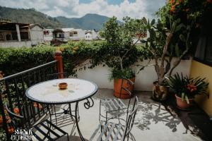 a table and chairs on a balcony with plants at Yellow House Hostel B&B in Antigua Guatemala