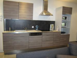 a kitchen with wooden cabinets and a sink at Côté Jardin in Saint-Jean-en-Royans