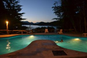 a person swimming in a swimming pool at night at Punta Manzano in Villa La Angostura