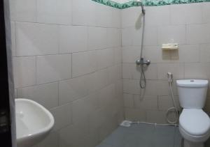 a bathroom with a shower and a toilet and a sink at Erwin's Guest Room in Sanur