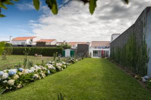 einen Garten mit weißen Blumen im Hof in der Unterkunft Surf Beach_Santa Barbara Secret Gardens in Ribeira Grande