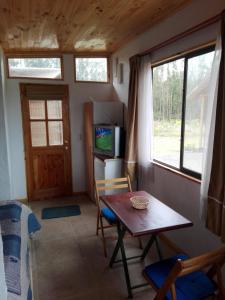 uma pequena sala de jantar com uma mesa e uma televisão em Cabañita Totoverde em El Totoral