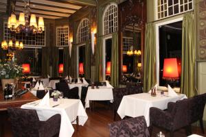 a restaurant with white tables and chairs and chandeliers at Augusta Hotel in IJmuiden