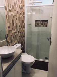 uma casa de banho com um WC e uma cabina de duche em vidro. em Boulevard Center no Guarujá