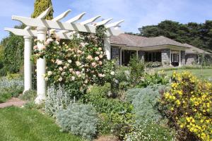 a white pergola in a garden with flowers at Historic Merryville Homestead in Murrumbateman