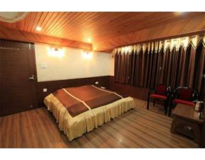 a bedroom with a bed and a chair in it at Excellent Stay at Mall in Nainital