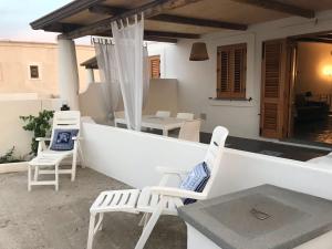 een patio met witte stoelen en een tafel bij Casa Nonna Maria in Stromboli